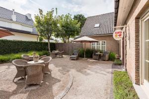patio z krzesłami, stołami i parasolem w obiekcie B&B visavis w mieście Wenduine