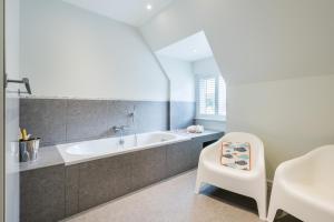 łazienka z wanną i białym krzesłem w obiekcie B&B visavis w mieście Wenduine +37 zdjęć