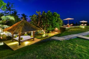 um jardim com um gazebo com um sofá branco em Villa Boutiq em Lovina