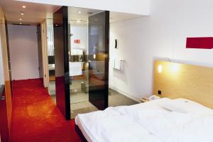 デュッセルドルフにあるINNSiDE by Meliá Düsseldorf Seesternの白いベッドとガラスの壁が備わるベッドルーム1室が備わります。