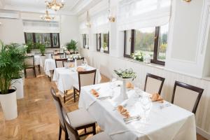 a restaurant with white tables and chairs and windows at Hotel Arkadia in Warsaw