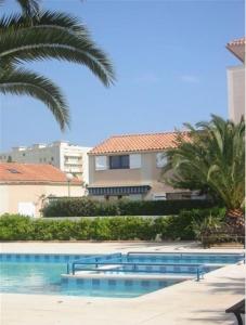 una piscina con palmeras y un edificio en Mas Provençal, en Le Lavandou