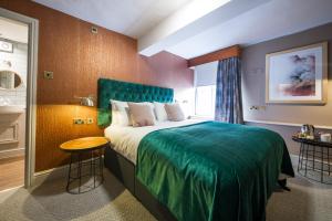 a bedroom with a large bed with a green bedspread at The Bulls Head by Innkeeper's Collection in Meriden