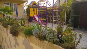 un jardín con un parque infantil con plantas y flores en Guest House Planet MOV, en Adler