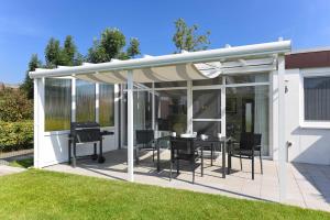 eine Pergola mit einem Tisch und Stühlen auf einer Terrasse in der Unterkunft Ferienhaus Meine Perle in Bensersiel