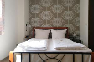 ein Bett mit weißer Bettwäsche und Kissen in einem Schlafzimmer in der Unterkunft Weinhaus Kurtrierer Hof in Leiwen