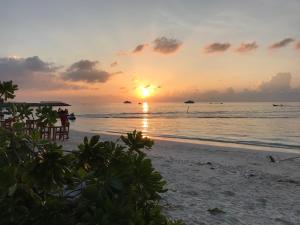 een zonsondergang op het strand met een groep mensen bij Sun Shine View in Maafushi