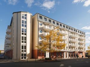 ein hohes weißes Gebäude mit einem Baum davor in der Unterkunft Best Western Hotel Nürnberg City West in Nürnberg