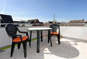 2 Stühle und ein Tisch auf dem Balkon in der Unterkunft Ferienwohnungen An Deck in Bensersiel