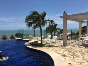 a swimming pool with a palm tree next to the ocean at Apartamento Imperial Porto Brasil in Pirangi do Norte