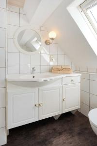 ein weißes Badezimmer mit Waschbecken und Spiegel in der Unterkunft Landhaus Meer in Neuharlingersiel