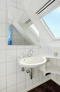a white bathroom with a sink and a skylight at Landhaus Meer in Neuharlingersiel