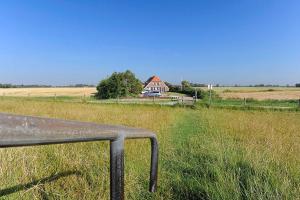 a bench in the middle of a field with a house at Landhaus Meer in Neuharlingersiel
