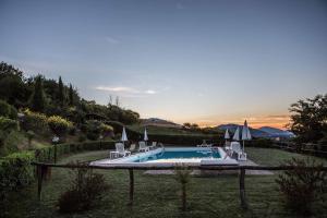 a pool with chairs and umbrellas in a yard at Il poggio dei tre contadini in Ponte Felcino