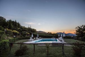 una piscina con sillas y sombrillas en un patio en Il poggio dei tre contadini, en Ponte Felcino