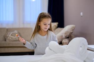 a little girl holding a toothbrush in a room at Airport Hotel Garni in Belgrade