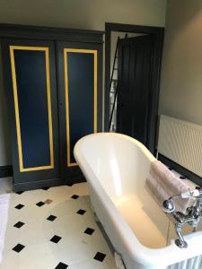 a white bath tub in a bathroom with a tile floor at Ellesmere House in Castle Cary
