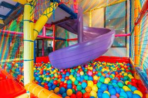 un parque infantil lleno de bolas y un tobogán púrpura en Mikołajki Resort Hotel & Spa Jora Wielka, en Mikołajki