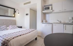 a kitchen with a white counter top and white appliances at Néméa Appart'hotel Green side Biot Sophia Antipolis in Biot