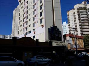 un edificio blanco alto con coches estacionados frente a él en Oft Plaza Oeste Hotel, en Goiânia