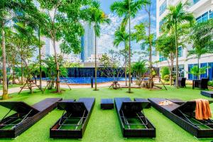a resort with a pool and tables and palm trees at Nam Talay Jomtien Beach - Rooftop Ocean View - Close to Beach, Pool & Gym in Na Jomtien