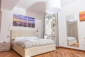Habitación blanca con cama y espejo en Le Tre Lune Suites, en Florencia