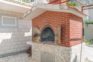 an outdoor brick pizza oven with a brick at Apartment Neda in Duće