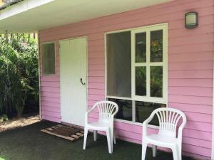 due sedie bianche sedute fuori da una casa rosa di Oasis a Sámara