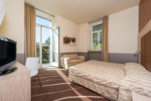 a bedroom with a bed and a television and a chair at Grand Hotel Riva in Riva del Garda