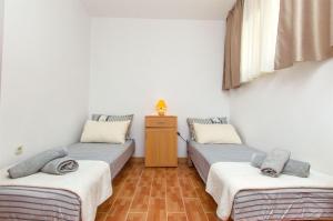 a room with two twin beds and a table at Apartments and Rooms Anita in Vrboska