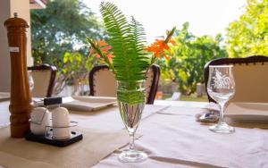 een glazen vaas met bloemen erin op een tafel bij The White House of Victoria Falls in Victoria Falls
