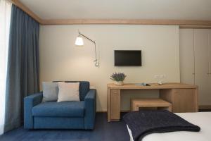 um quarto de hotel com uma cadeira azul e uma televisão em Hotel Meublè Sertorelli Reit em Bormio