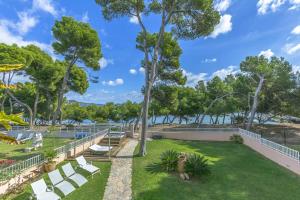 ein Park mit weißen Bänken und Bäumen und dem Wasser in der Unterkunft YupiHome Villa Ran de Mar in Port d'Alcúdia