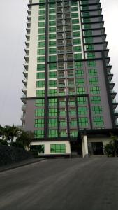 a tall building with green windows on the side of it at Dusit Grand Condo View Apartment in Jomtien Beach