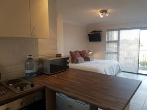 a room with a bed and a kitchen with a counter top at San Norina Gardens in Bloubergstrand