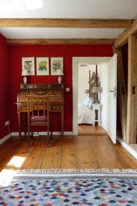 a red room with a desk and a bedroom at Villa am Trumpf - Design-Appartements im Naturgarten am See in Melzow +31 photos