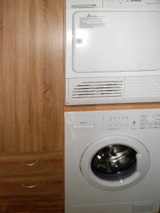 eine weiße Waschmaschine neben einem Holzschrank in der Unterkunft Ferienwohnung Anke - Apartment 3 in Heinsberg