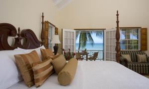 a bedroom with a bed and a view of the ocean at Villa Beach Cottages in Castries