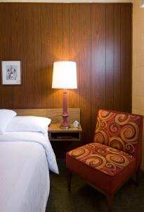 ein Schlafzimmer mit einem Bett, einem Stuhl und einer Lampe in der Unterkunft Sunset Motel Moriarty in Moriarty