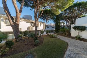 un jardin en face d'une maison arborée dans l'établissement BmyGuest - Quinta do Lago Mezzanine Apartment, à Almancil