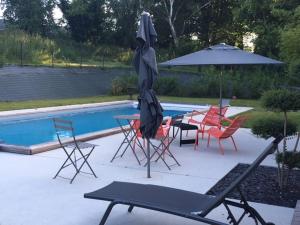 - un groupe de chaises et un parasol à côté de la piscine dans l'établissement Maison d'hôtes les Escures, à Acigné