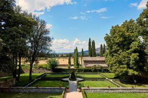 un jardín con una fuente y árboles y un edificio en Villa di Piazzano - Small Luxury Hotels of the World, en Cortona