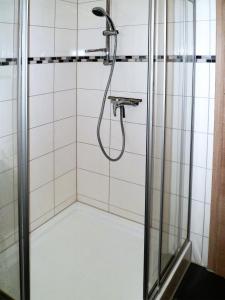 um chuveiro na casa de banho com azulejos brancos em Ferienwohnung Anke - Apartment 3b em Heinsberg