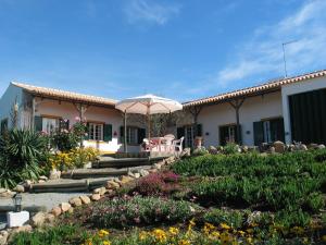 a house with an umbrella and a garden with flowers at Monte da Pereira in São Cristóvão