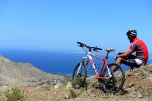 a man sitting next to a bike on a hill at Casale Panayiotis in Kalopanayiotis