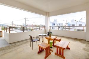 Habitación con balcón con mesas y sillas. en Condominium Aoi Sanmyaku, en Okinawa City