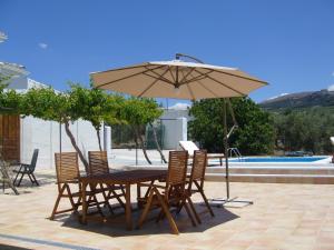 una mesa con sillas y una sombrilla junto a la piscina en B&B Lasnavillasmm en Montefrío