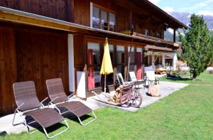 a group of chairs and an umbrella in front of a house at Landhaus KATRIN in Holzgau