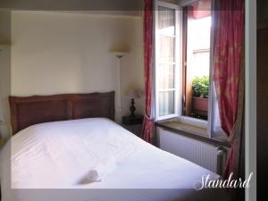 a bedroom with a white bed with a window at Logis Le Relais Champenois in Sézanne