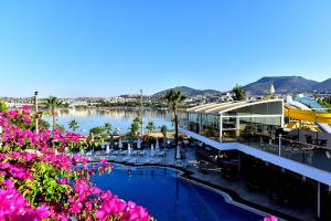 un complexe avec une grande piscine et des fleurs roses dans l'établissement Tropicana Beach, à Gumbet